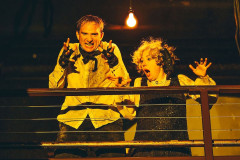 Andrey Burkovskiy and Chulpan Khamatova, dusty and wide-eyed, leaning over a balcony rail in Delirium at the Space at Irondale. Photo by Austin Ruffer