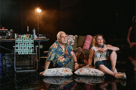 Michael Mulheren and Victoria Clark sitting on cushions on the floor of the research tent in Human Things at the West End Theatre. Photo by Emilio Madrid