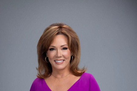 Kelli Finglass in a magenta dress against a plain grey studio background