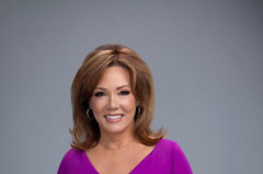 Kelli Finglass in a magenta dress against a plain grey studio background
