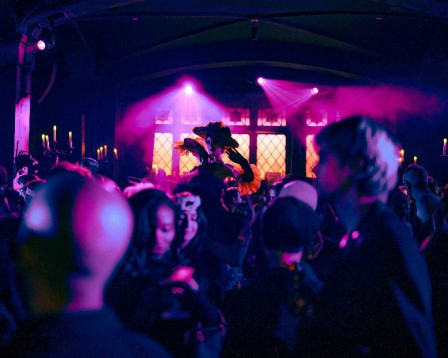 Masked guests beneath pink light at Le Bal Macabre, the Halloween soirée staged by Masquerade in New York. Photo by Mark Minton