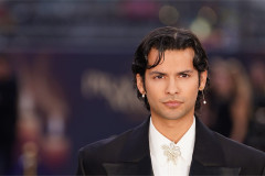 Xolo Maridueña on a red carpet in a black jacket and white shirt with a floral brooch. Photo by Ian West/PA Images