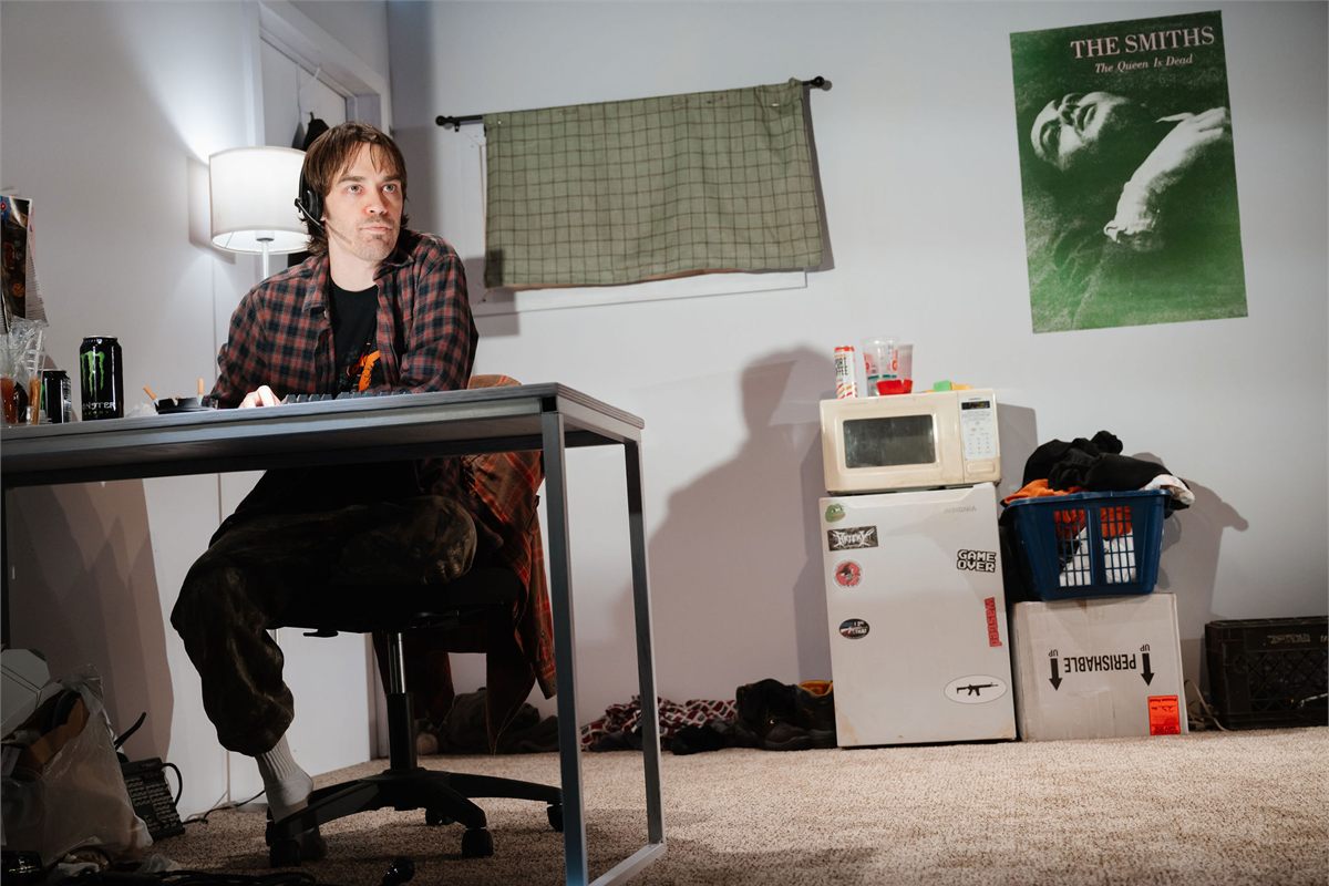 Zachary Desmond as Miller at his desk in a bare basement room in Degenerates at Playwrights Horizons