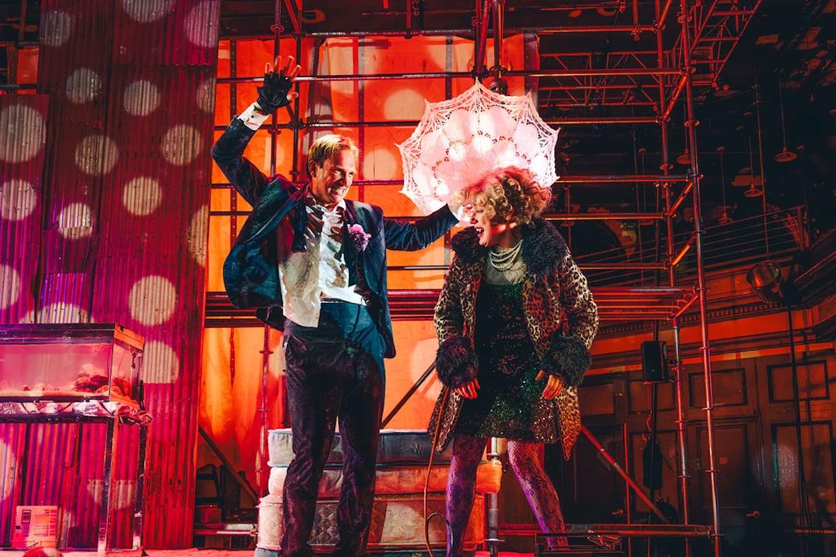 Andrey Burkovskiy, arm raised, and Chulpan Khamatova under a lace parasol in pink polka-dot light in Delirium at the Space at Irondale. Photo by Austin Ruffer Andrey Burkovskiy, arm raised, and Chulpan Khamatova under a lace parasol in pink polka-dot light in Delirium at the Space at Irondale. Photo by Austin Ruffer