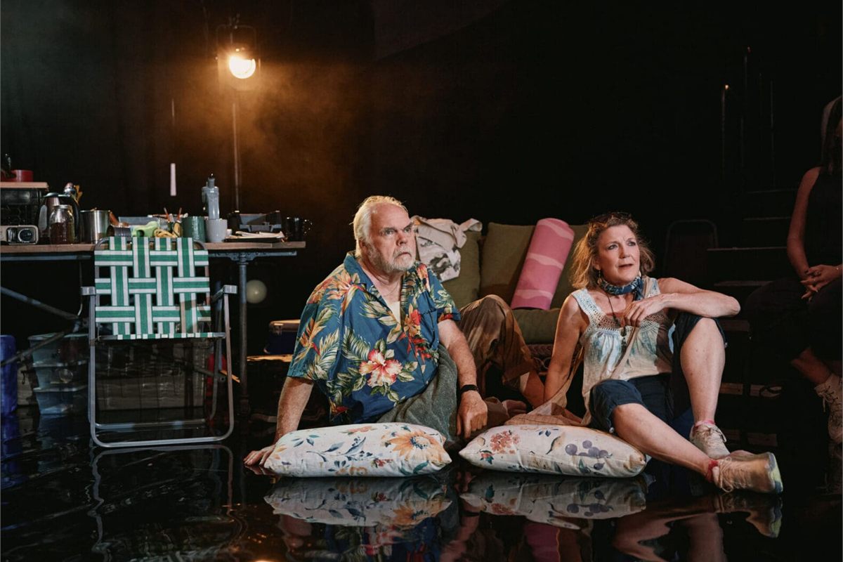 Michael Mulheren and Victoria Clark sitting on cushions on the floor of the research tent in Human Things at the West End Theatre. Photo by Emilio Madrid