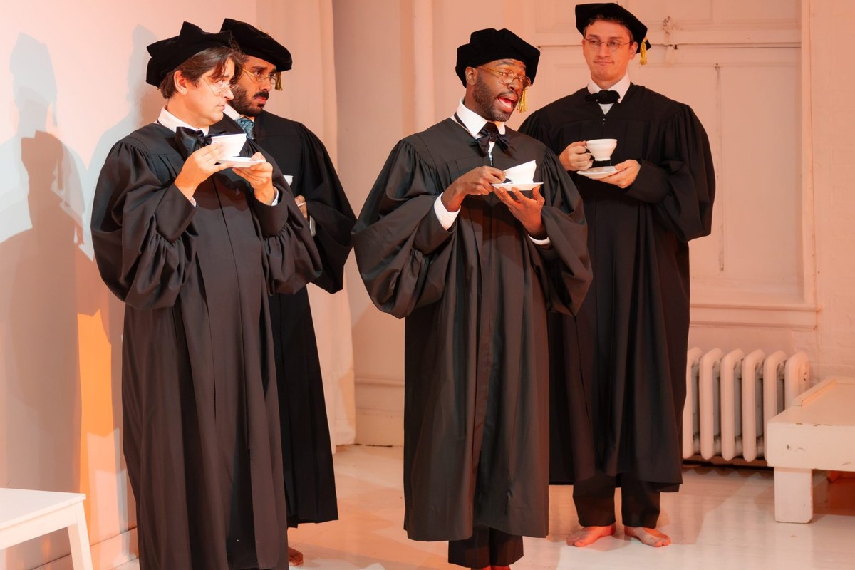Four Oxford dons in academic gowns and caps, barefoot, holding teacups in The Invention of Love