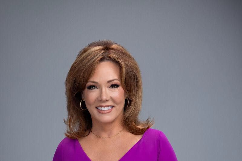 Kelli Finglass in a magenta dress against a plain grey studio background
