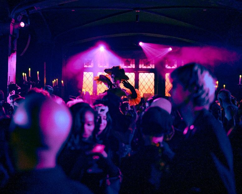 Masked guests beneath pink light at Le Bal Macabre, the Halloween soirée staged by Masquerade in New York. Photo by Mark Minton